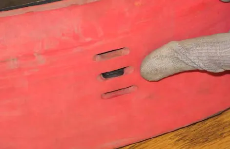 Finger pointing at a tab hooked through a hole in the squeegee blade