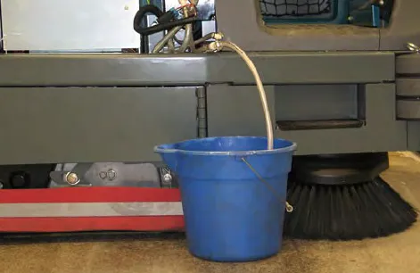 Drain hose running into an empty bucket beside the machine