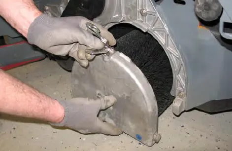 Hands removing the idler plate from the scrub head