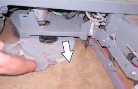 Hand squeezing the spring handles so the disk brush drops to the floor, with an arrow pointing down