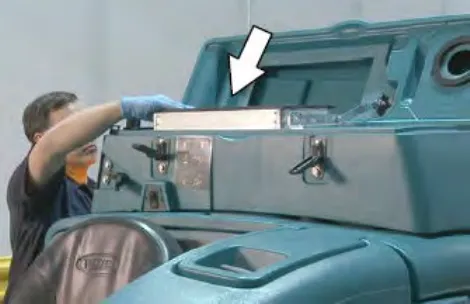 Operator removing the live wand vacuum filter from the vacuum chamber, with an arrow pointing to the filter
