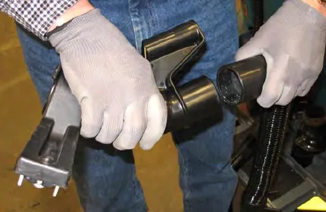 Gloved hands joining the vacuum wand nozzle to the nozzle hose