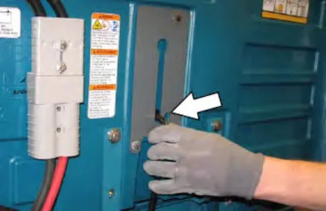 Hand lifting the strap in the open battery compartment, with an arrow pointing to it
