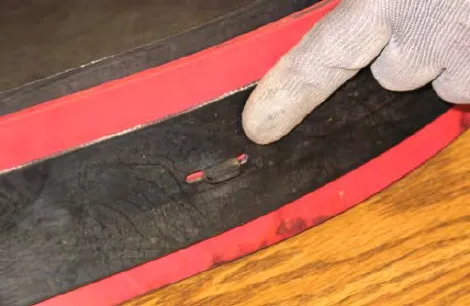 Finger pointing at a tab hooked through a hole in the squeegee blade
