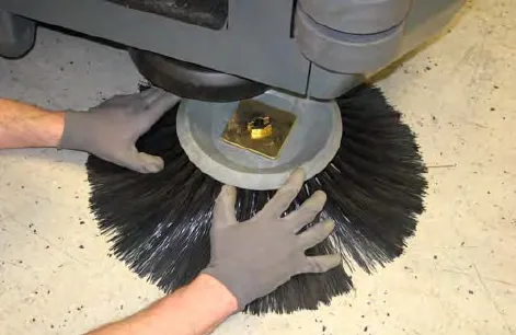 Hands removing the sweeping side brush and retaining washer from under the assembly