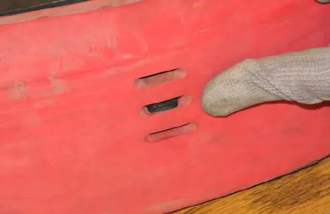 Finger pointing at a tab hooked through a hole in the squeegee blade