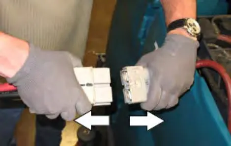 Hands pulling the charger connector apart from the battery cable connector, with arrows showing the directions
