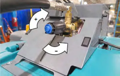 Pressure adjustment knob on the washer system with a curved plus arrow for clockwise and a curved minus arrow for counterclockwise