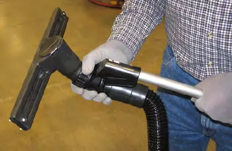 Gloved hands tightening the vacuum wand handle into the vacuum wand nozzle