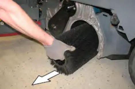 Hand pulling a cylindrical brush out of the scrub head, with an arrow showing the direction