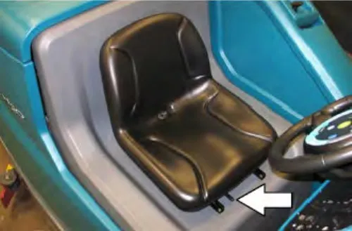 Operator seat with an arrow pointing at the front-to-back adjustment lever under the seat