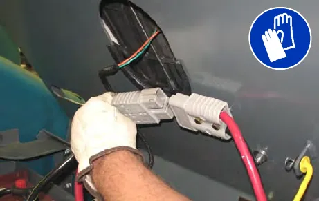 Gloved hand disconnecting the machine connector from the batteries
