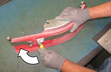 Gloved hand fastening the retaining band latch, with an arrow showing the direction