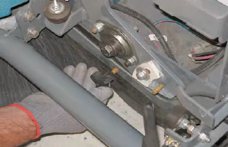 Gloved hand removing a knob from the Pre-Sweep side skirt plate