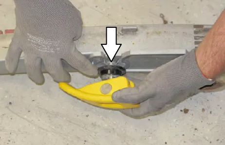 Gloved hands sliding a yellow retainer out of the squeegee assembly, with an arrow pointing down
