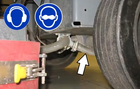 Hose at the solenoid valve inlet port under the frame, with an arrow pointing to it; hearing and eye protection are required