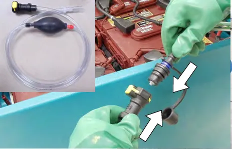 The hand pump hose with bulb, and gloved hands connecting it to the battery fill hose coupler