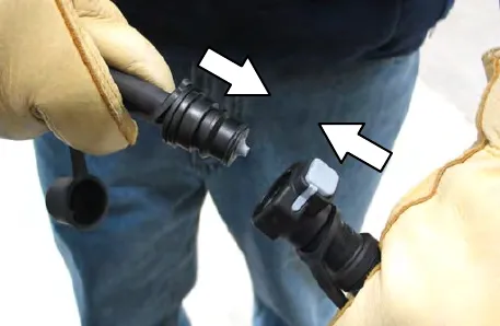 Gloved hands connecting the fill regulator to the battery fill tube, with arrows showing the two halves coming together