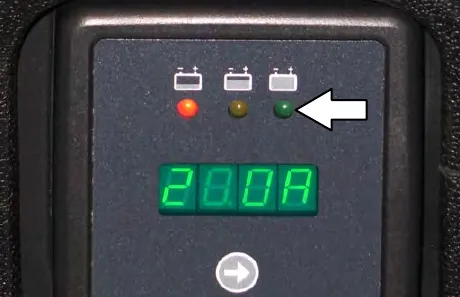 On-board charger panel with red, yellow and green indicator lights, a digital display and an arrow pointing to the green light