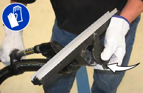 Gloved hands fitting the vacuum wand cap into the vacuum port, wearing gloves