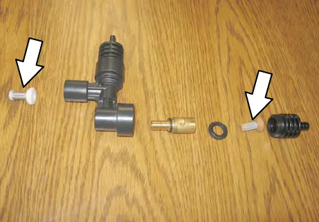 Disassembled injector on a table with arrows pointing to the two small filters