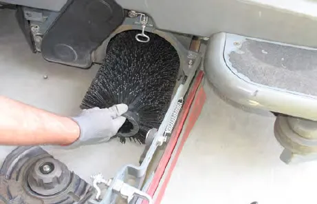 Gloved hand pulling the cylindrical brush out of the scrub head