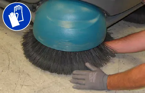 Hand reaching into the center of the Pre-Sweep disk side brush; gloves must be worn