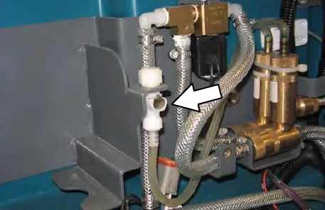 Compartment wall with an arrow pointing to the storing plug for the supply hose connector