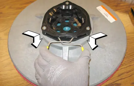 New side brush with arrows pointing to the spring handles being held open