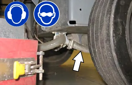 Hose at the solenoid valve inlet port under the frame, with an arrow pointing to it; hearing and eye protection are required