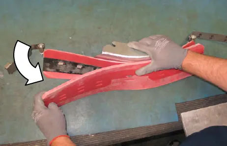 Hands peeling the squeegee blades off the squeegee frame, with an arrow showing the direction