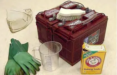 Battery with a scrub brush, safety glasses, rubber gloves, measuring cup and a box of baking soda