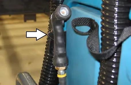 Spray nozzle placed on its hook, with an arrow to the hook
