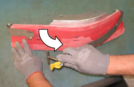 Hands pulling the retaining band off the side brush squeegee, with an arrow showing the direction