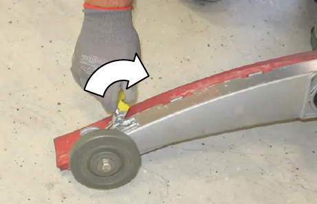 Gloved hand fastening the retainer latch at the end of the squeegee assembly, with an arrow showing the direction