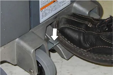 Operator's shoe stepping on the transport release pedal, with an arrow showing the pedal direction