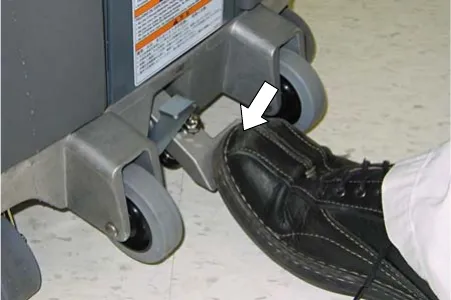 Operator's shoe stepping on the scrub head lift pedal to raise the scrub head
