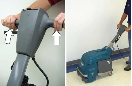 Hands pulling the start triggers on the handle, and an operator scrubbing a corridor floor with the T1