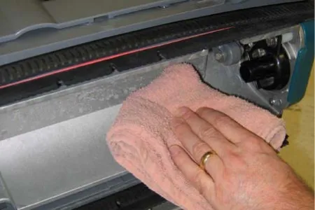 Wiping the underside of the scrub head with a cloth
