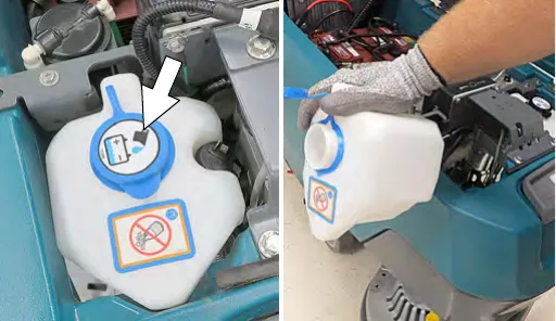 Lifting the automatic battery watering tank out of the machine to empty it
