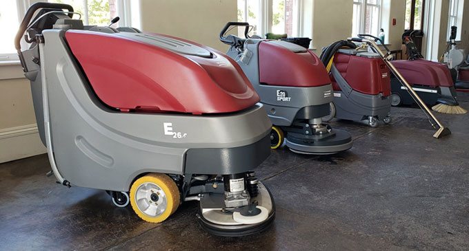 Walk-behind floor scrubbers lined up on a showroom floor